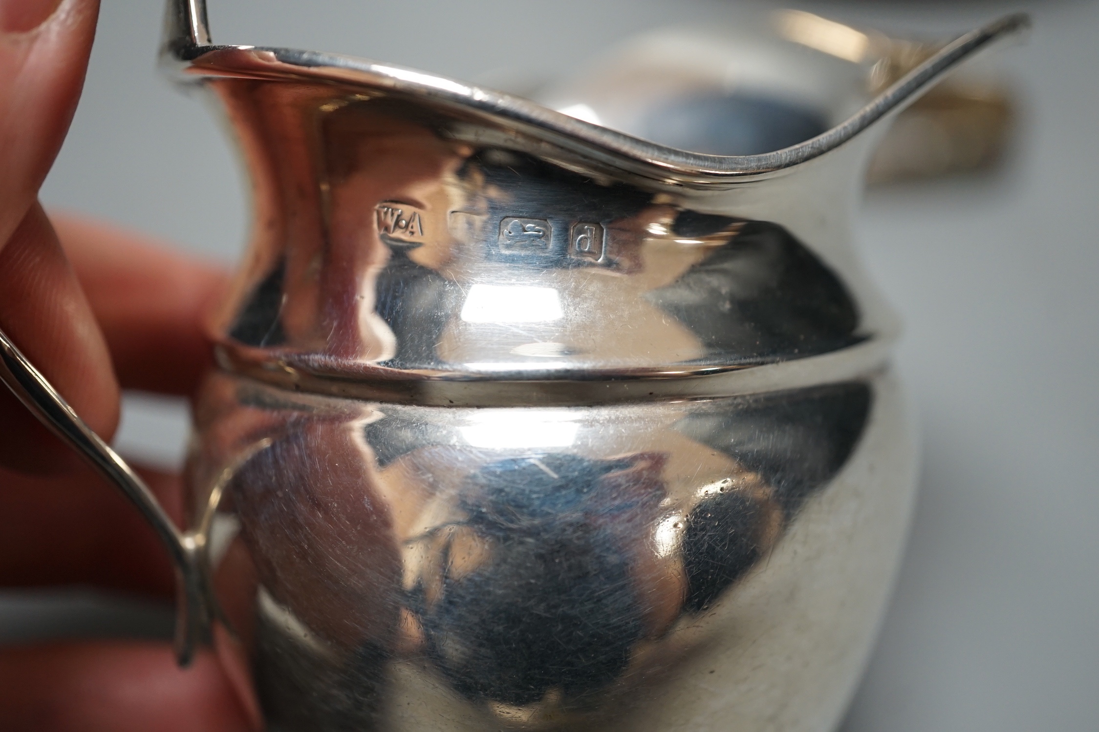 A George IV silver circular teapot, Craddock & Reid, London, 1824, a later silver cream jug and pair of silver sugar tongs, gross 19oz.